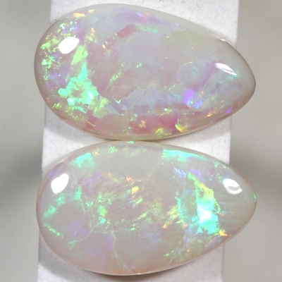 SOLID SEMI BLACK OPALS Matching pair. bright green and orange rolling flashes over a hue of purple